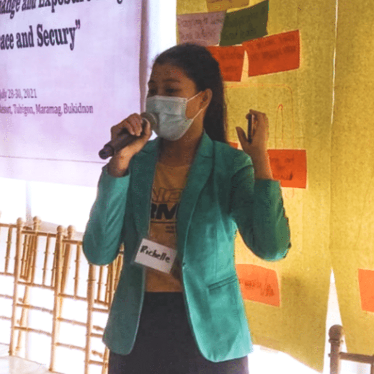 Woman from Mindanao speaking into microphone with mask