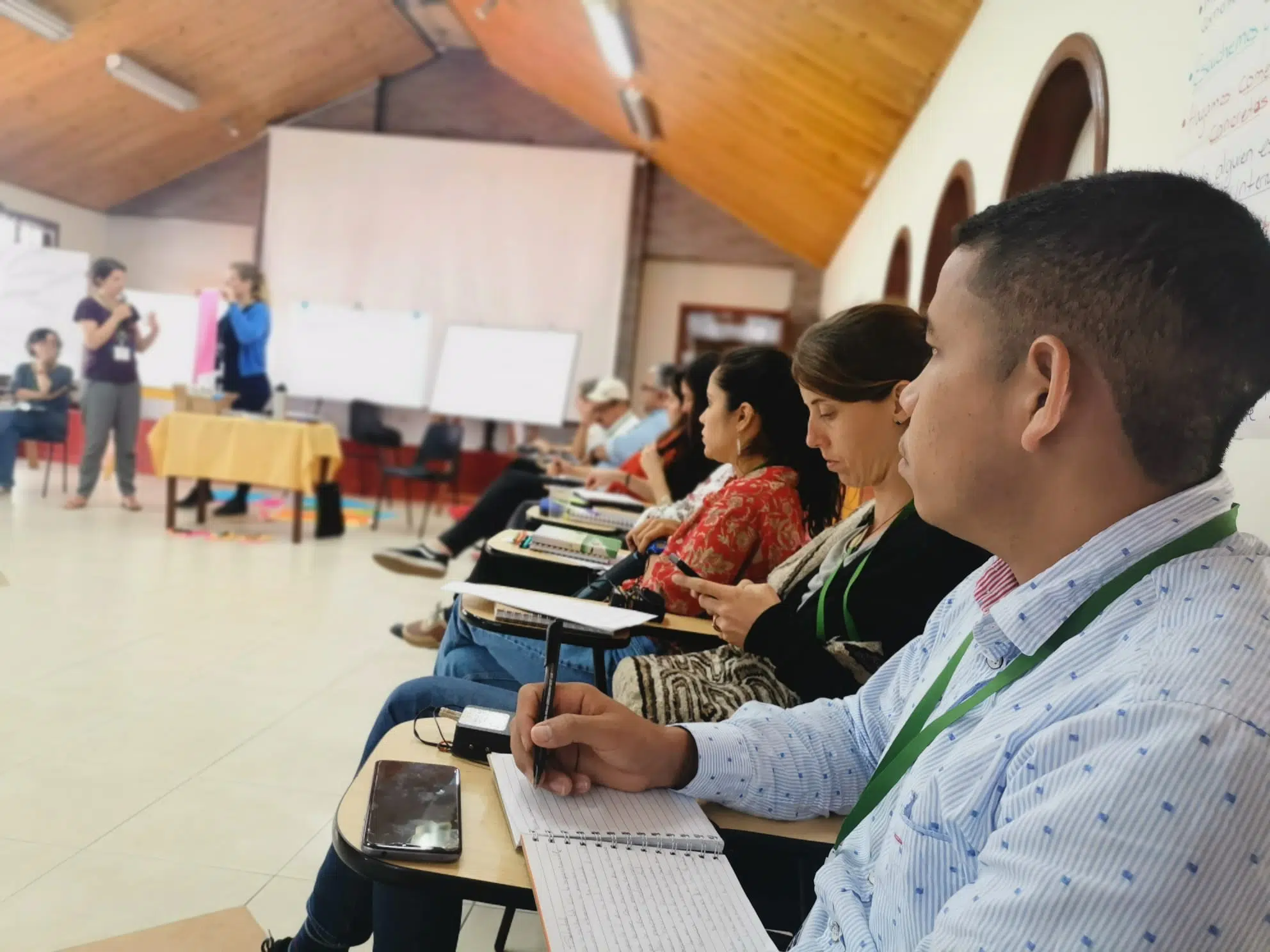 Zwei Menschen singen und lächeln und halten ein Schild mit thailändischen Buchstaben während eines Trainings in Südthailand. NP-Mitarbeiter lächeln neben zwei Personen.