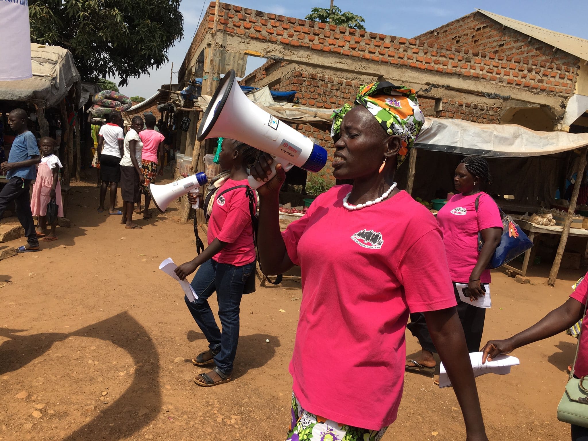 In Mundri, a woman using a megaphone, marches with several others through a local town during 16 Days of Activism.
