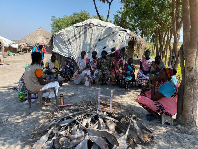 A group of women in a circle while a nonviolent peaceforce staff member speaks to them outdoors. Location is Lelo, Malakal County, Upper Nile, South Sudan. 