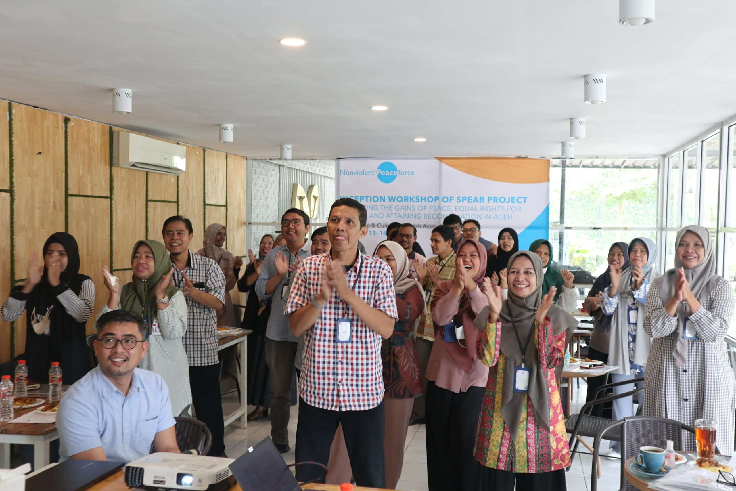 Several people clapping at an event in Aceh, Indonesia organized by Nonviolent Peaceforce and community partners.