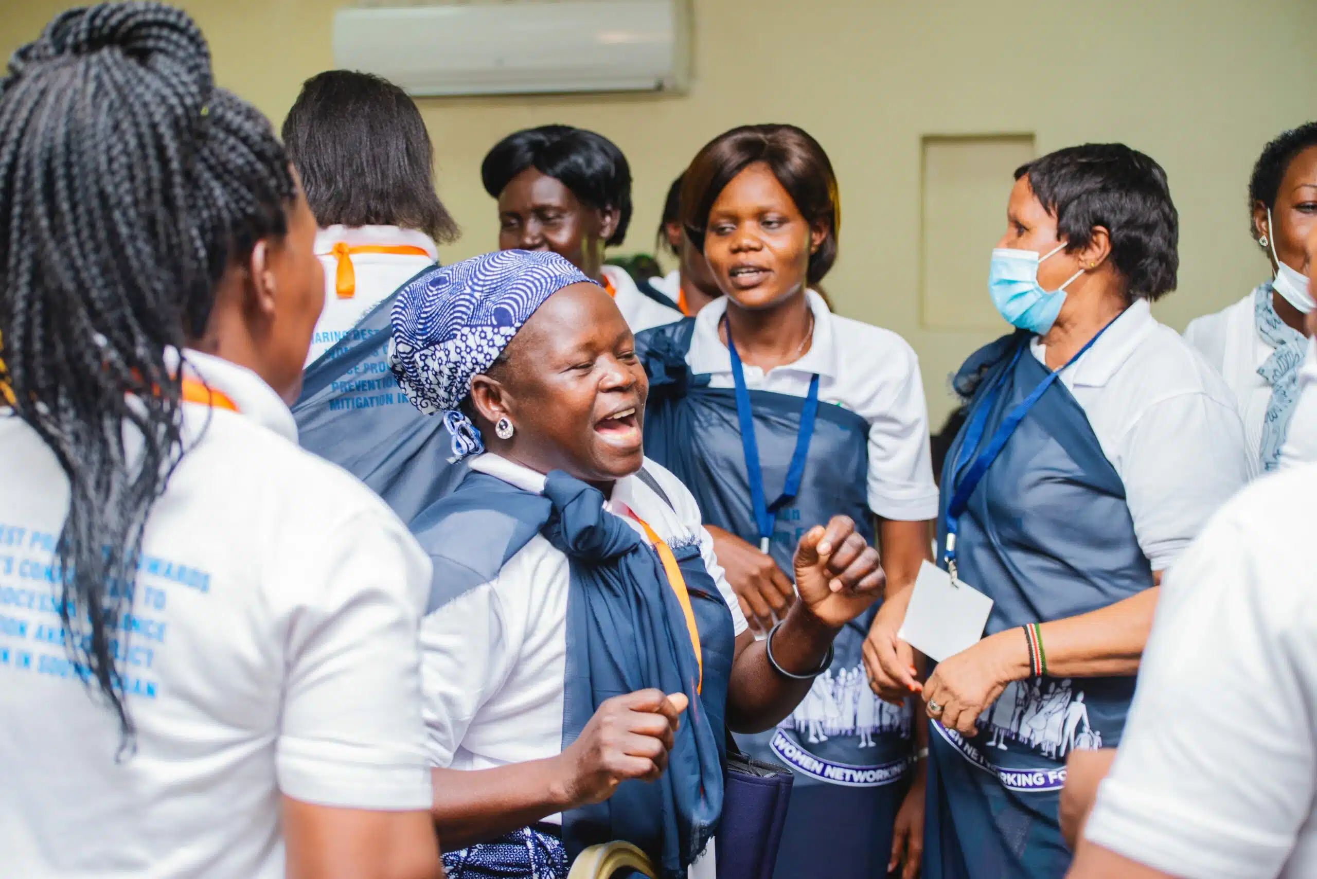 A woman with her eyes closed and looks like she is dancing, looks happy. She is standing in the middle of a group of women.