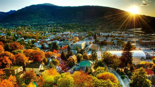 Fall colorful trees in a Canadian town nestled under rolling mountains and a sunset