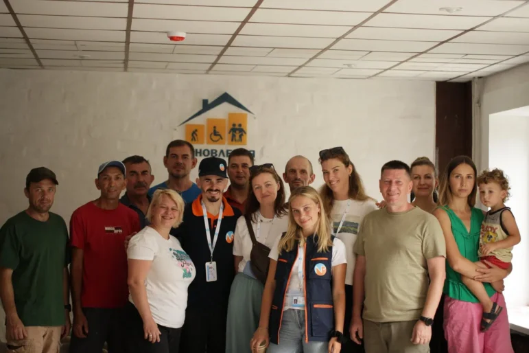 A group of NP staff members and local actors stand smiling for a photo.