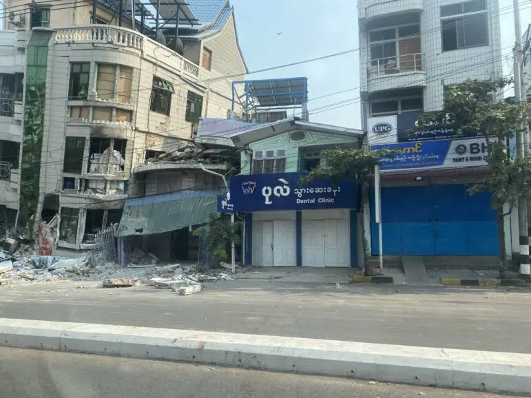 Bâtiments visiblement endommagés suite à un important tremblement de terre au Myanmar. Sur un petit bâtiment, on peut lire « Clinique dentaire ».