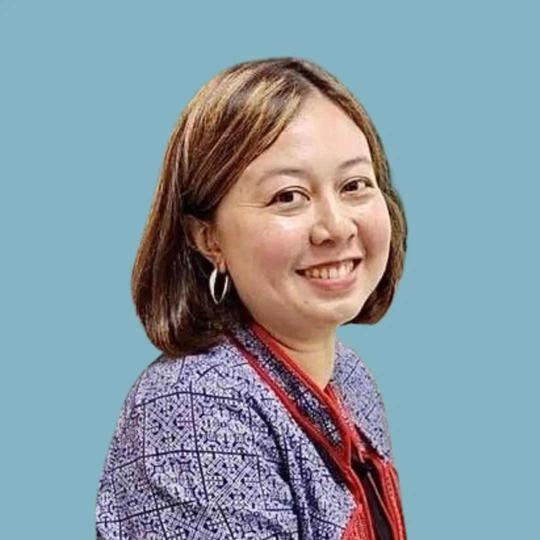 Woman sitting for headshot, blue background