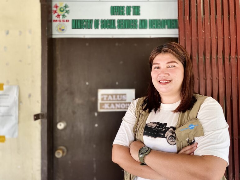 Sweetsel, Women-Friendly Space Facilitator stands in front of a door, smiling with arms crossed, at a Women Friendly Space location in BARMM.