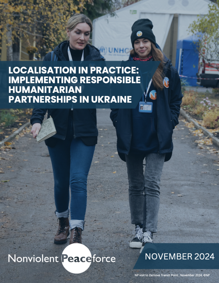 Two staff members wearing NP badges are bundled in winter coats and talking to one another while walking along an empty street in Ukraine.