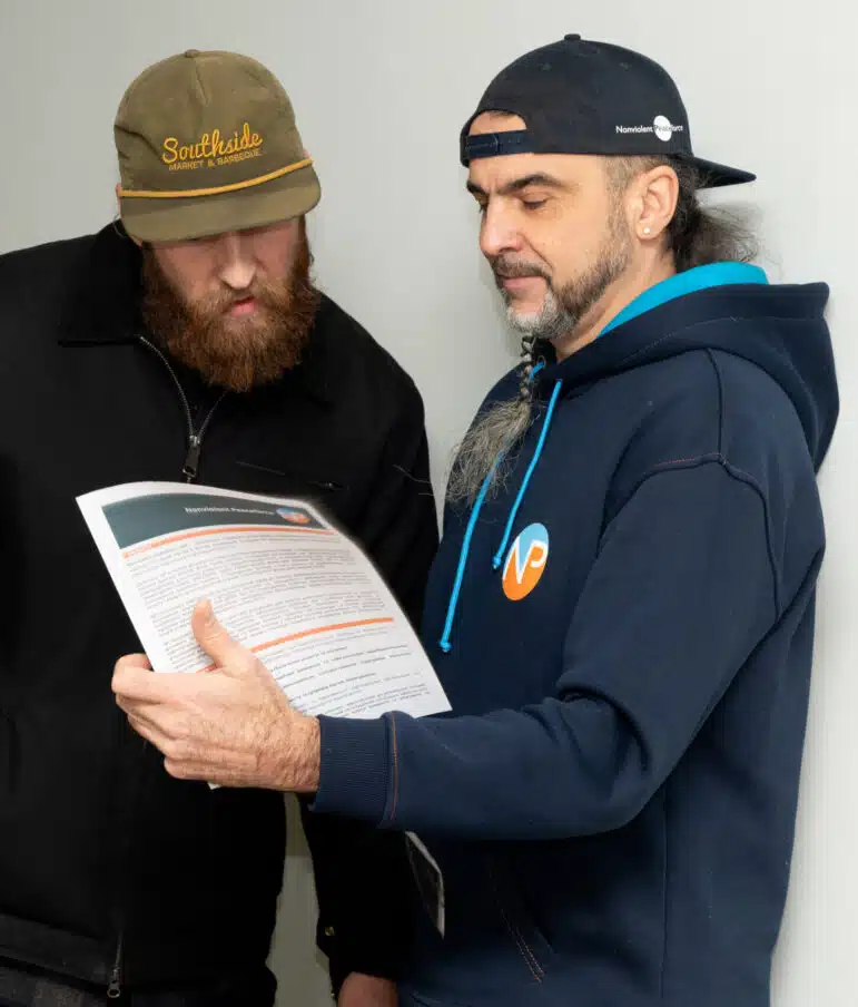 NP Ukraine staff works with local community partners. Two people are standing while reading through a NP document together.
